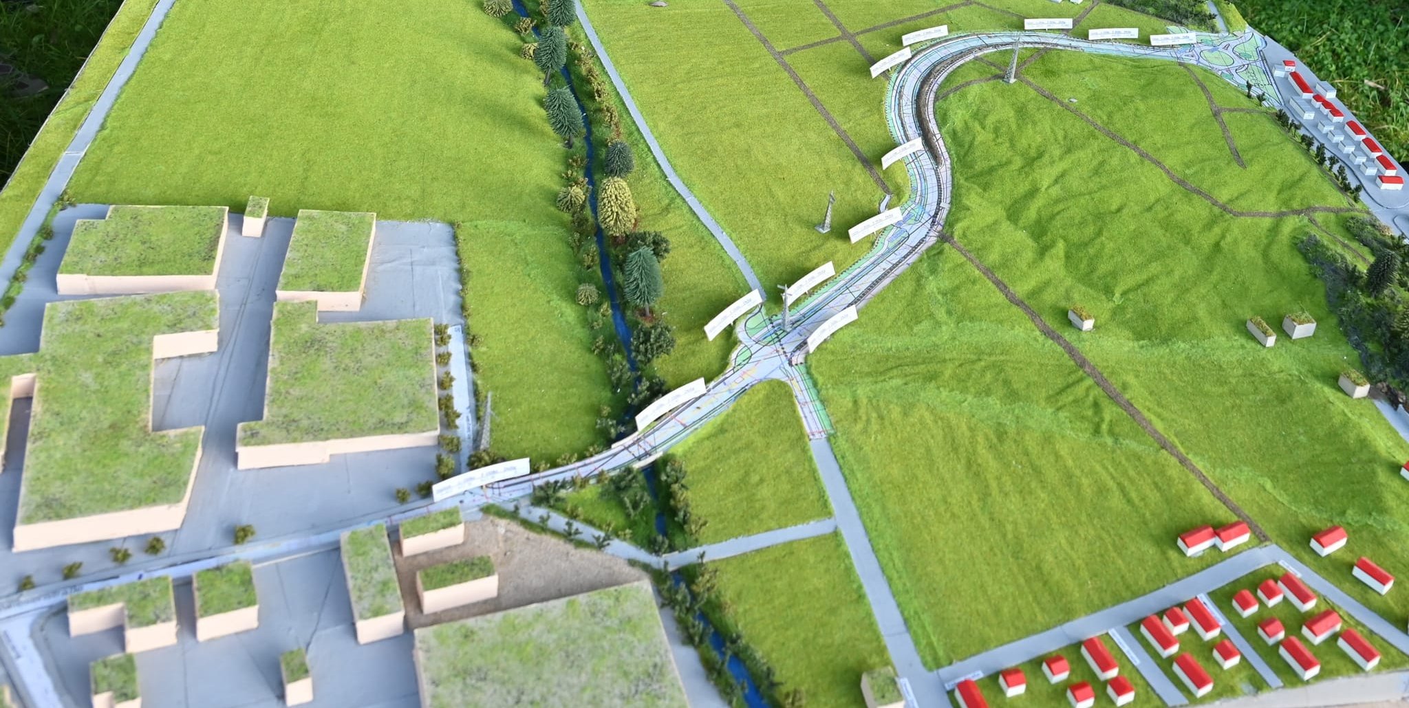 Die Osttangente im Modell. Sie überquert aus dem Gewerbegebiet Ost (links unten) kommend (Hutwiesenstraße) auf einem Damm den Planbach im Hölzertal, führt in einer Schleife um den Gollenberg herum und mündet an einem Kreisverkehr (rechts oben), von dem aus auch die Zufahrt zum Sportgelände an den Buchen abgeht, in die Alte Stuttgarter Straße. Auf dieser geht es weiter zum Aspenschopf in Richtung Stuttgart und Sindelfingen oder auf die Südtangente in Richtung B 464. Die Häuserzeile am rechten Bildrand gehört zum innerörtlichen Teil der  Alten Stuttgarter Straße. Bild: Reichert