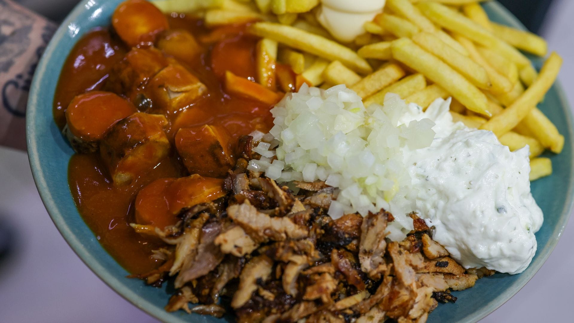 Imbiss mit Gehalt: Currywurst (links), Pommes frites mit Mayonnaise (oben) und Gyrosfleisch mit Zwiebeln und Tzatziki.