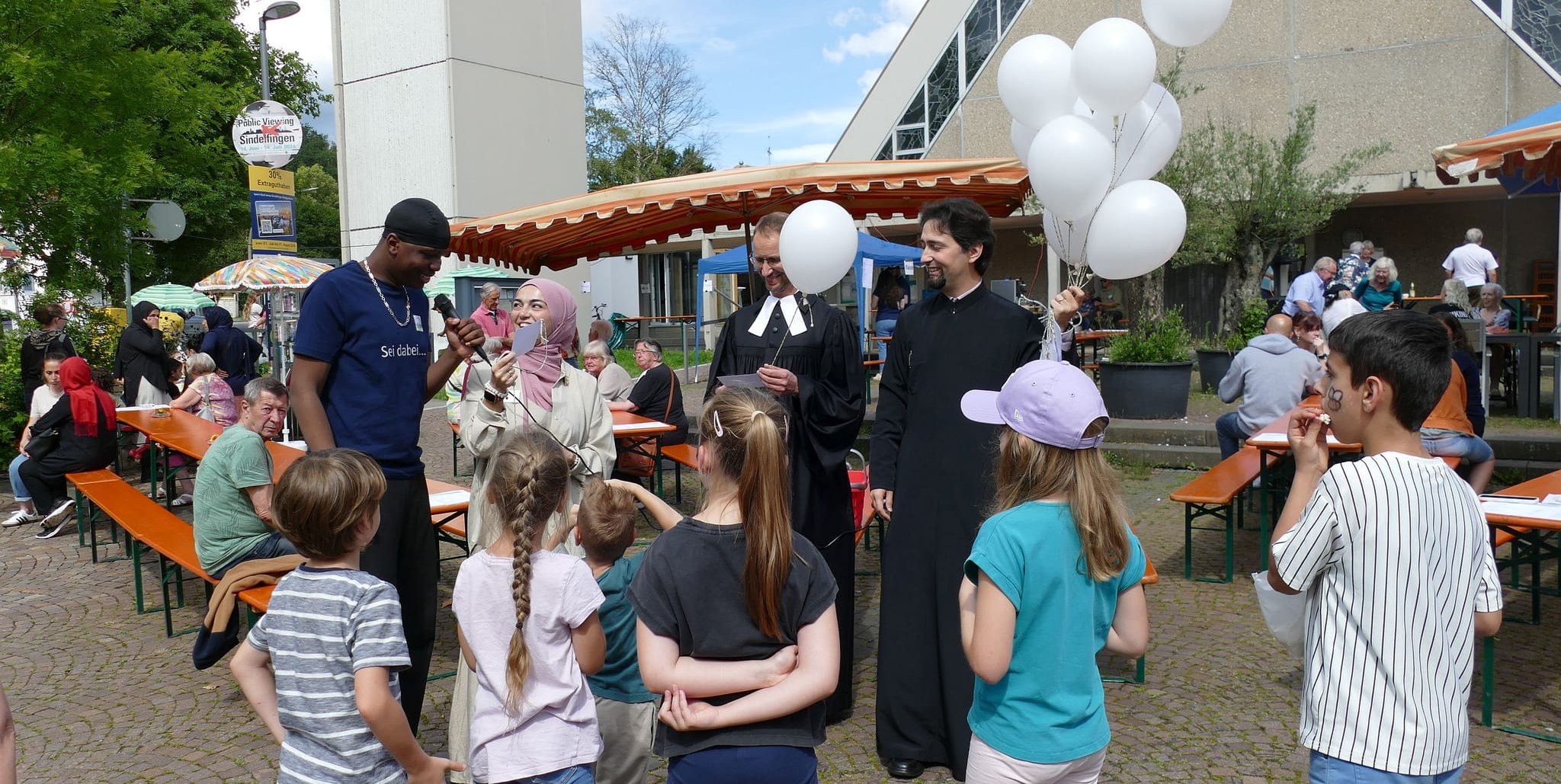 Auf unserem Foto (von links): Benje Kuntima, der spontan die Friedensbitten mit vorgelesen hat, Gökce Er, Pfarrer Manuel Hörger und Priester Stefan Arghir, davor die Kinder, die die Karten mit den Luftballons in den Himmel fliegen ließen.