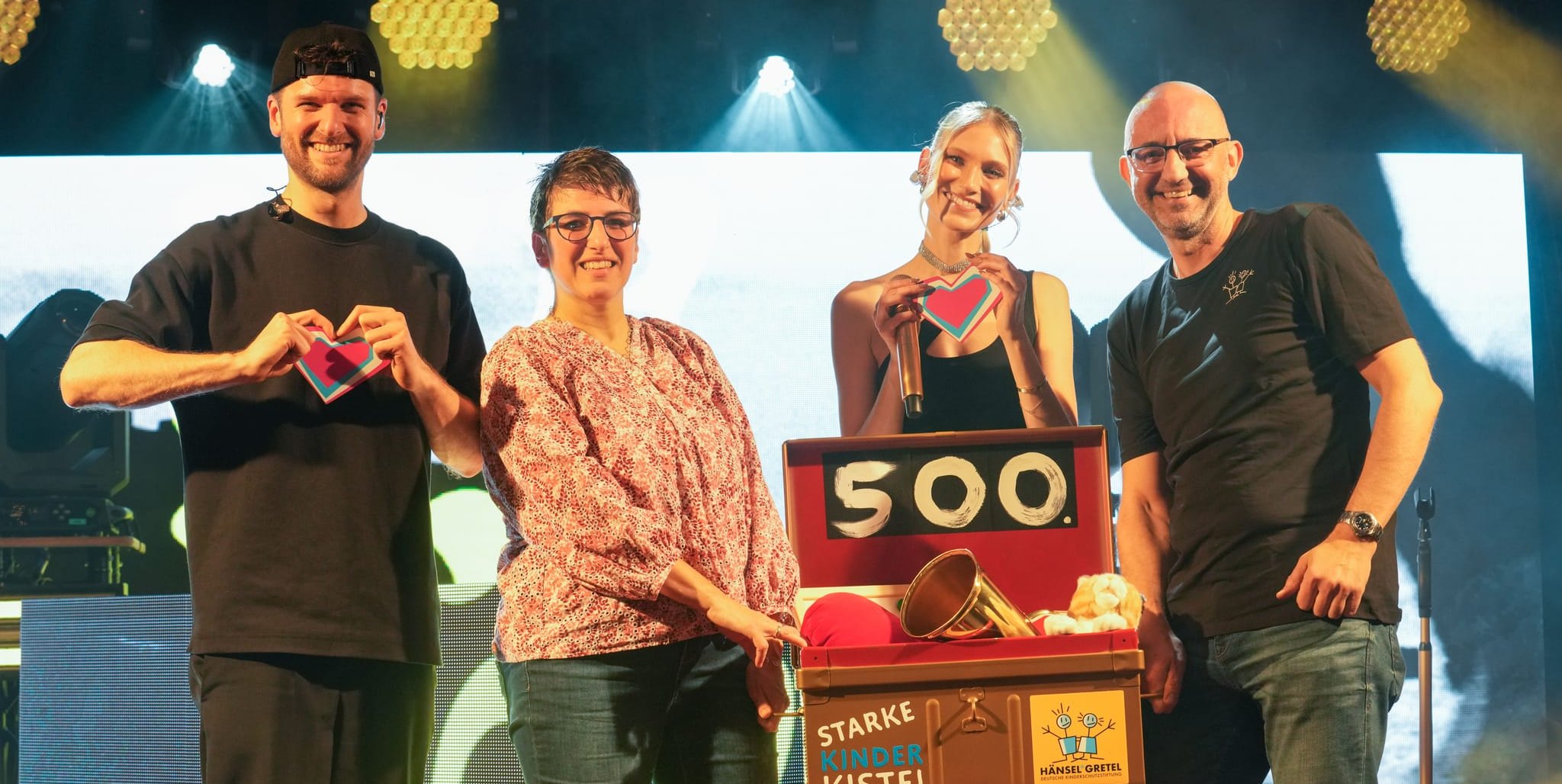Carolin Niemczyk und Daniel Grunenberg alias Glasperlenspiel mit Dorothee Gebel (Thamar Böblingen) und Jerome Braun (Deutsche Kinderschutzstiftung Hänsel+Gretel) mit der 500. „Starke Kinder-Kiste“.