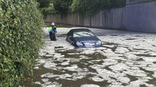 Nach schweren Unwettern steht ein Auto auf einer überfluteten Straße in Immenstadt. (Archivbild)