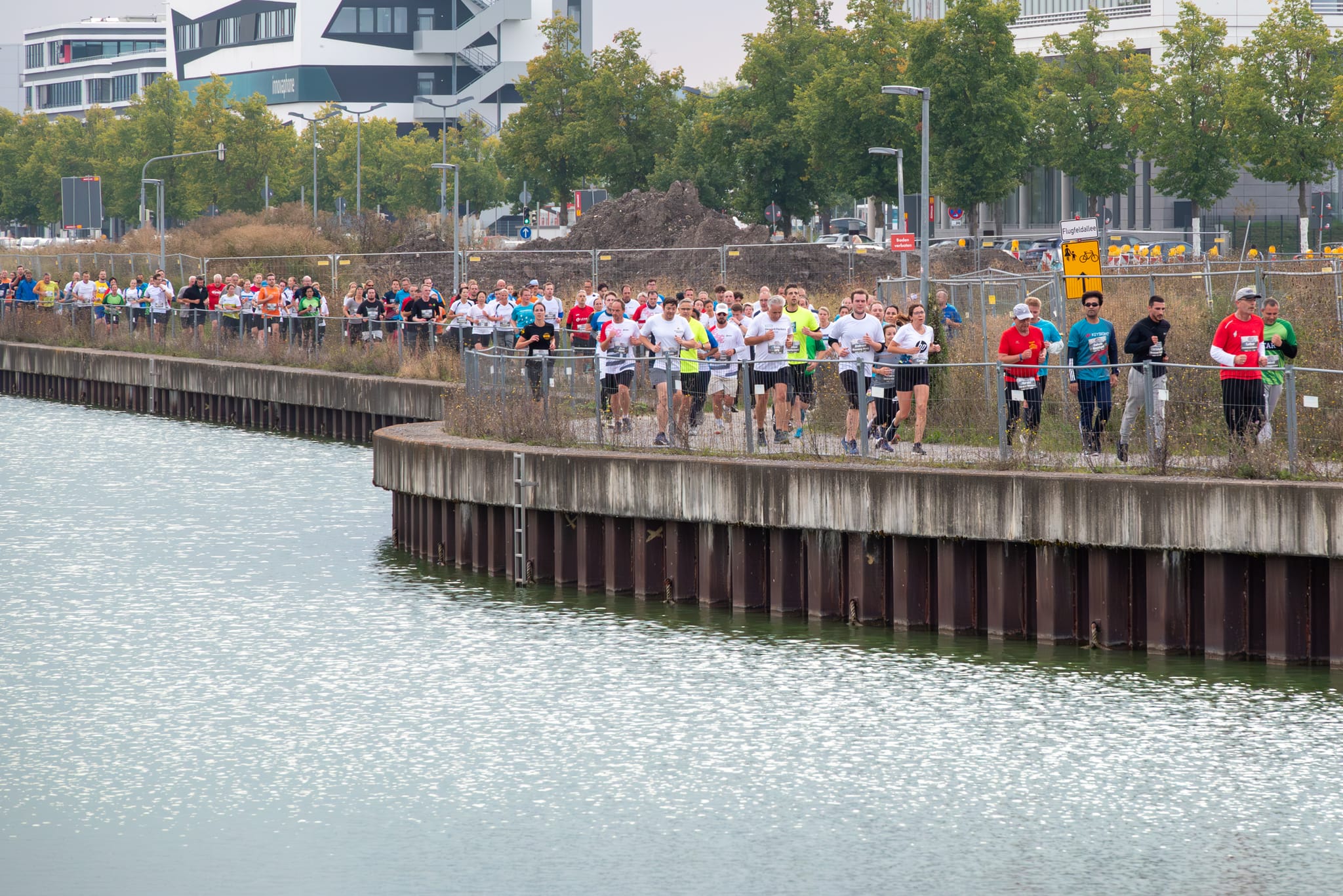 Wie an einer Schnur gezogen laufen die Starter des Firmenlaufs am Langen See auf dem Flugfeld. Bild: Nüßle