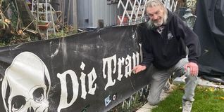 Andreas Ankele in seinem Garten, wo ein Banner an die Traube erinnert.