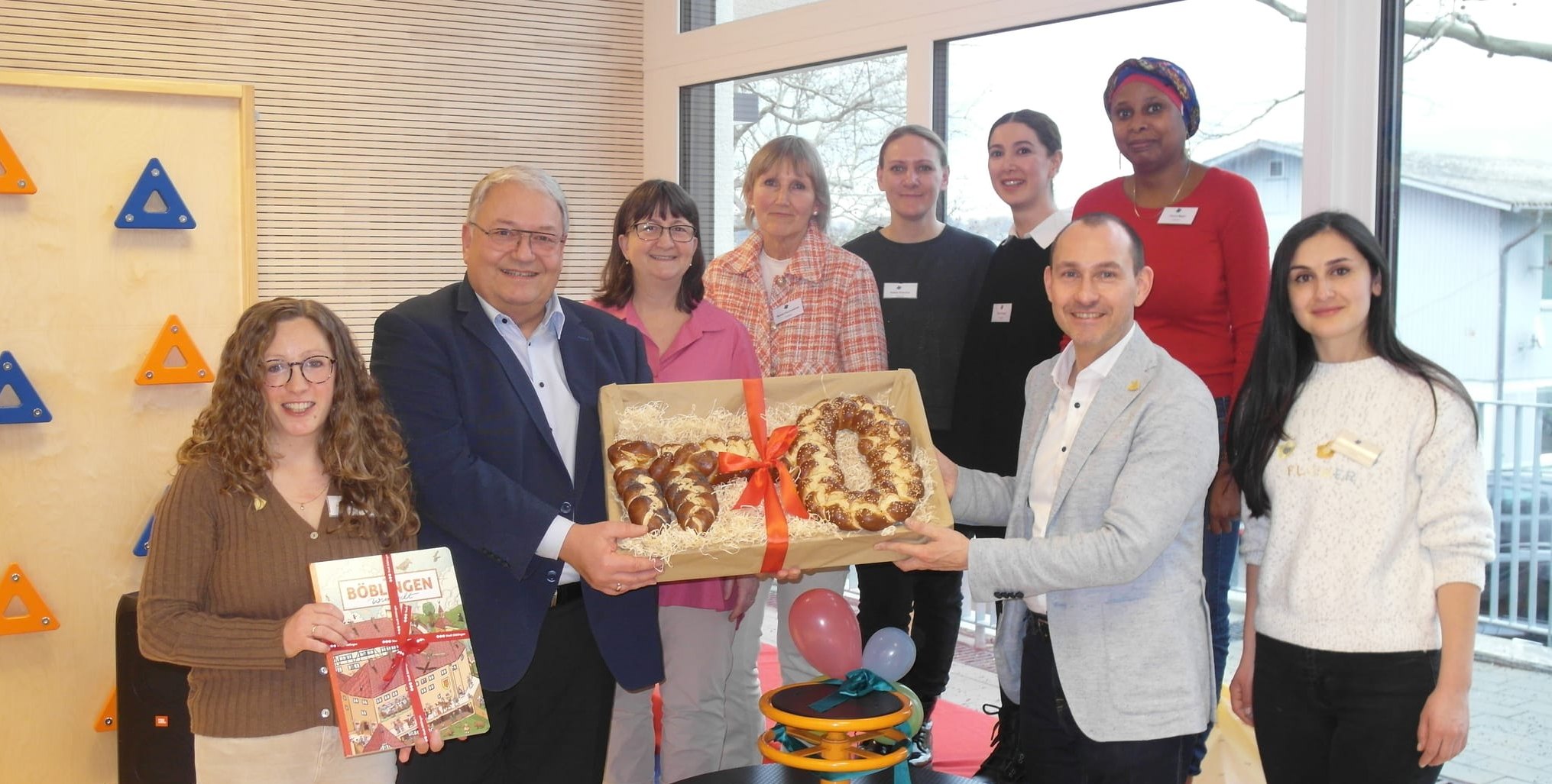 Gemeinsam mit dem Kita-Team haben Einrichtungsleiterin Lisa Landwehr-Luz (links), BGG-Geschäftsführer Rainer Ganske (am Brezel-Schlüssel links) und Böblingens Oberbürgermeister Dr.  Stefan Belz (am Brezel-Schlüssel rechts) die Eröffnung der Böblinger Kita Eugen-Bolz-Straße 47/1 gefeiert.