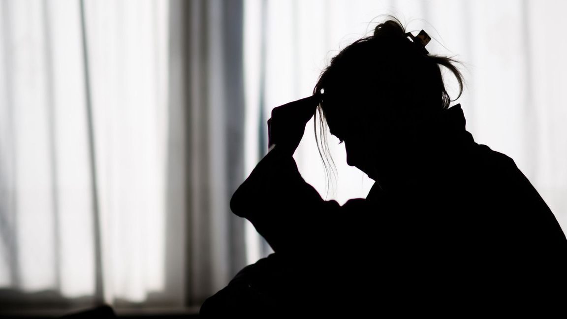 Silhouette einer Frau vor einer hellen Fensterfront