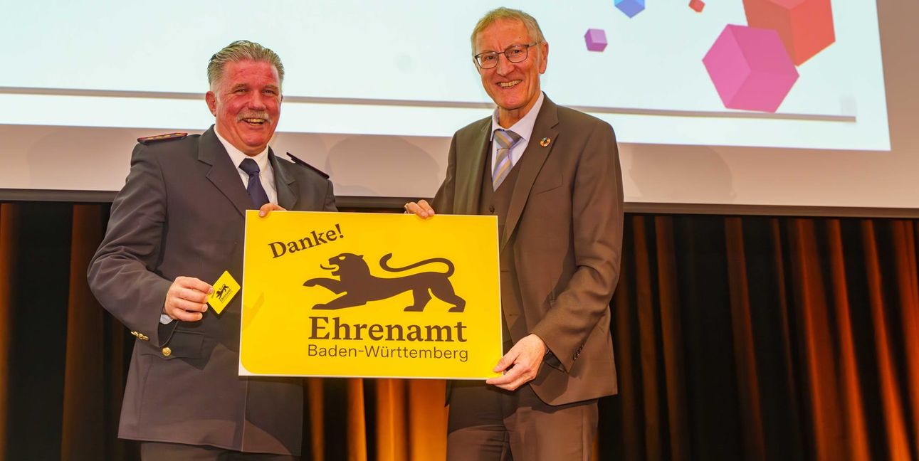 Landrat Roland Bernhard (rechts) übergibt die erste Ehrenamtskarte an den Vorsitzenden des Kreisfeuerwehrverbandes Böblingen Markus Priesching.	Bild: Dettenmeyer