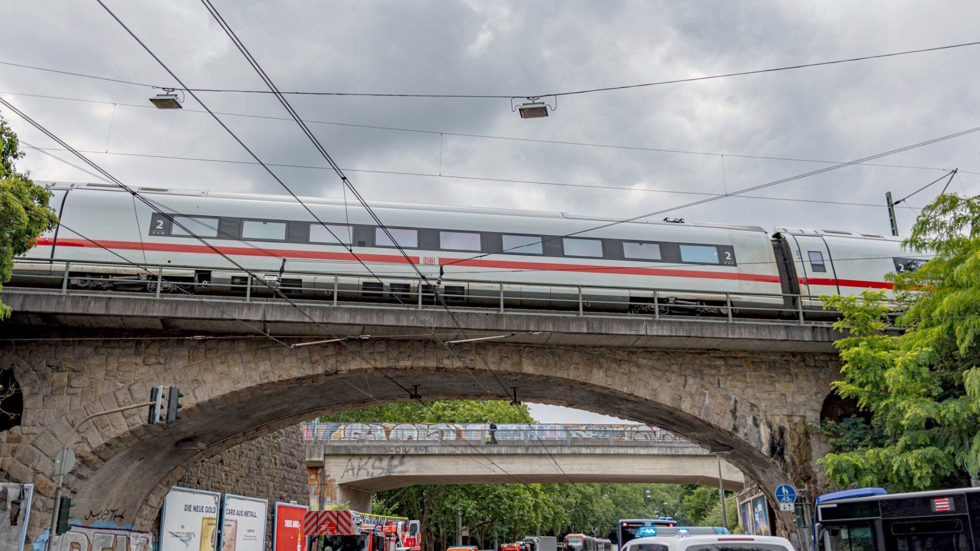 Einsatzkräfte von Polizei und Feuerwehr stehen an einer Eisenbahnunterführung am Bergischen Ring, auf der ein ICE liegengeblieben ist.