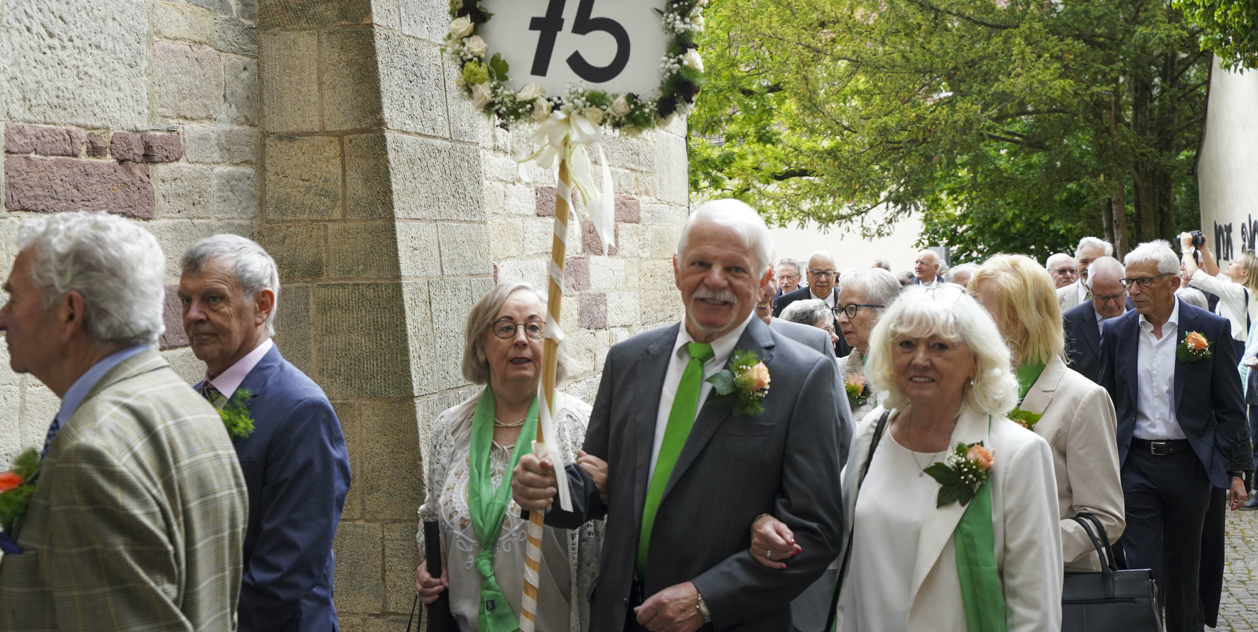 Willi Wolf reckt – sichtbar für alle – ein Schild mit der Zahl „75“ für den Jahrgang 1949 in die Höhe, als es in die Martinskirche geht.