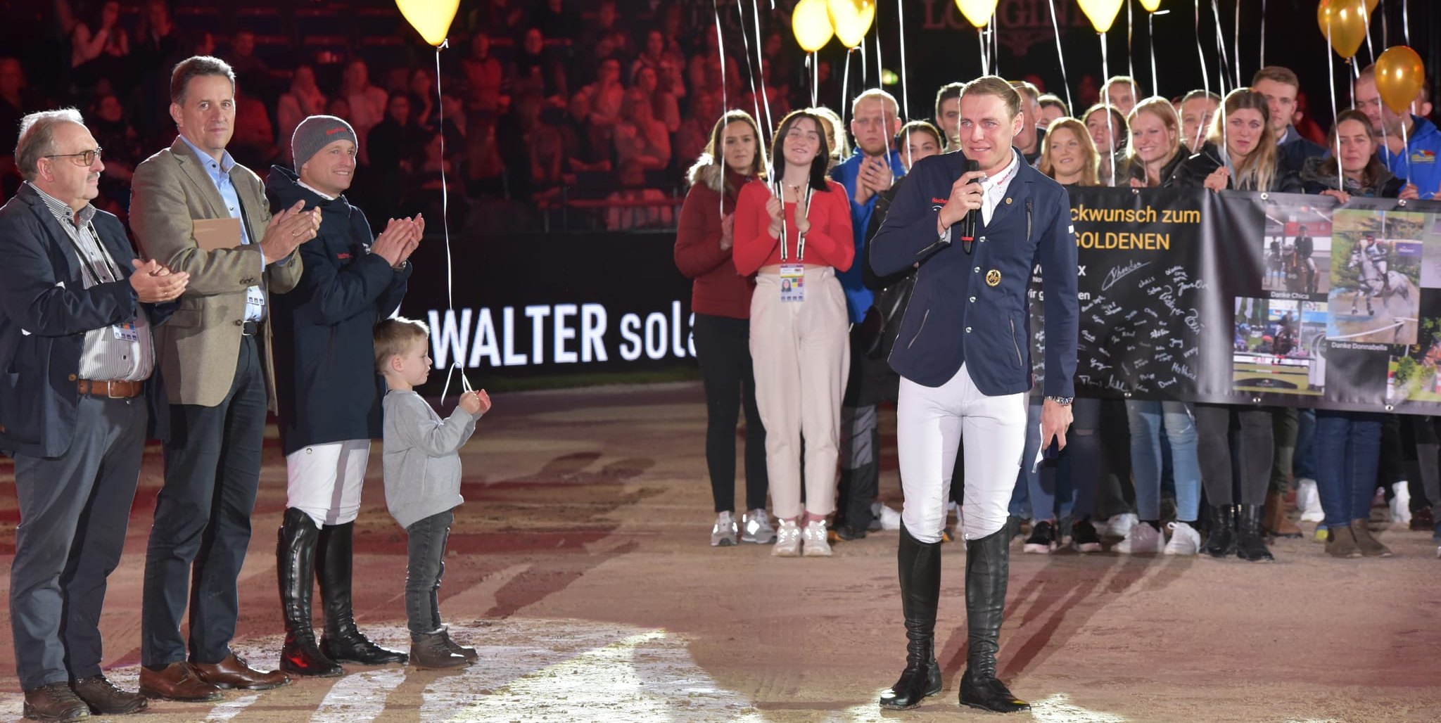 Sven Lux bei seiner bewegernden Ansprache.  Das goldene Reitabzeichen bekam er vorher von Olympiasieger Michael Jung (Dritter von links mit Sohn Lio). Bild: Häusler