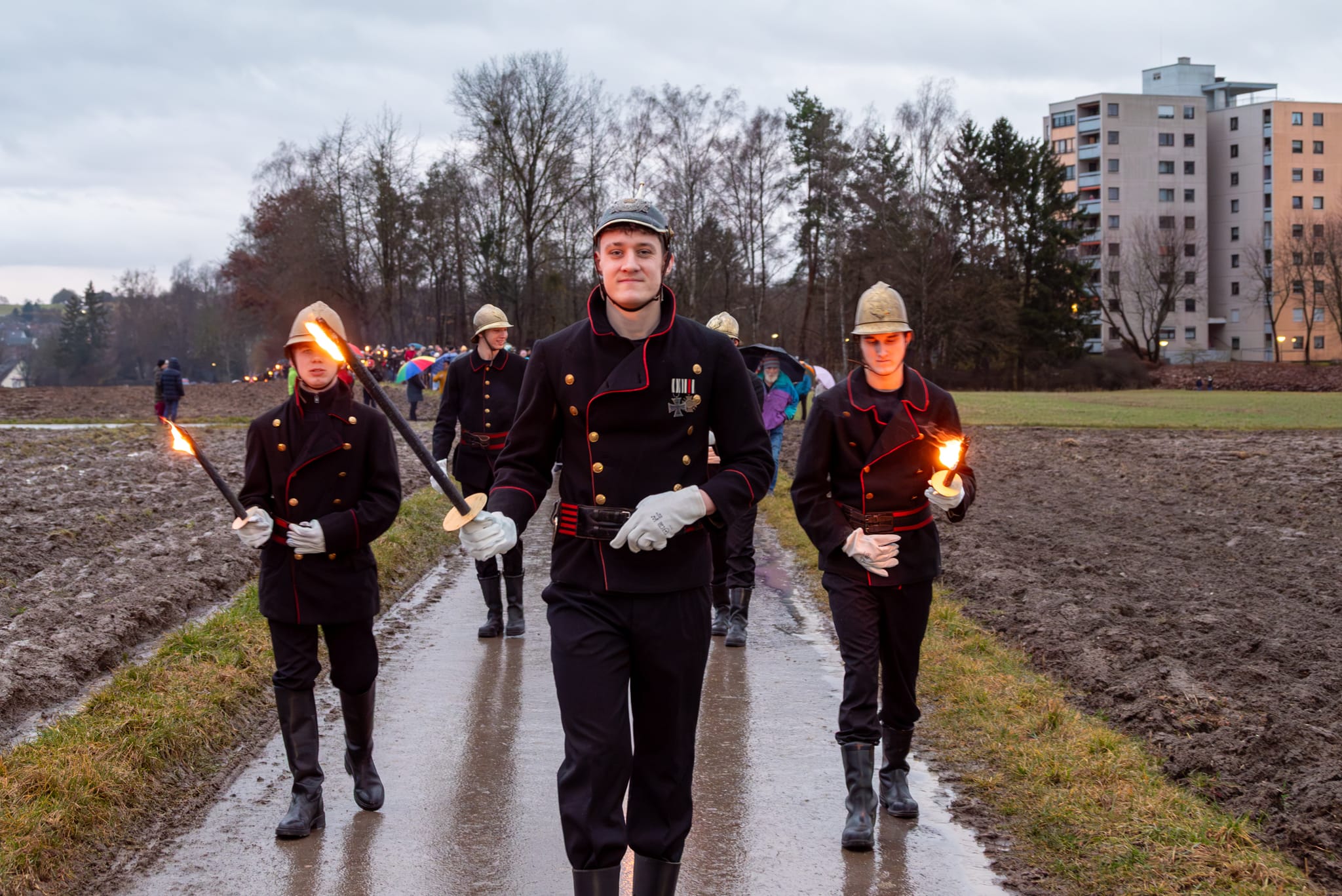 Mit Fackeln und in historischer Uniform führen die Feuerwehrkameraden den Fackelzug an.