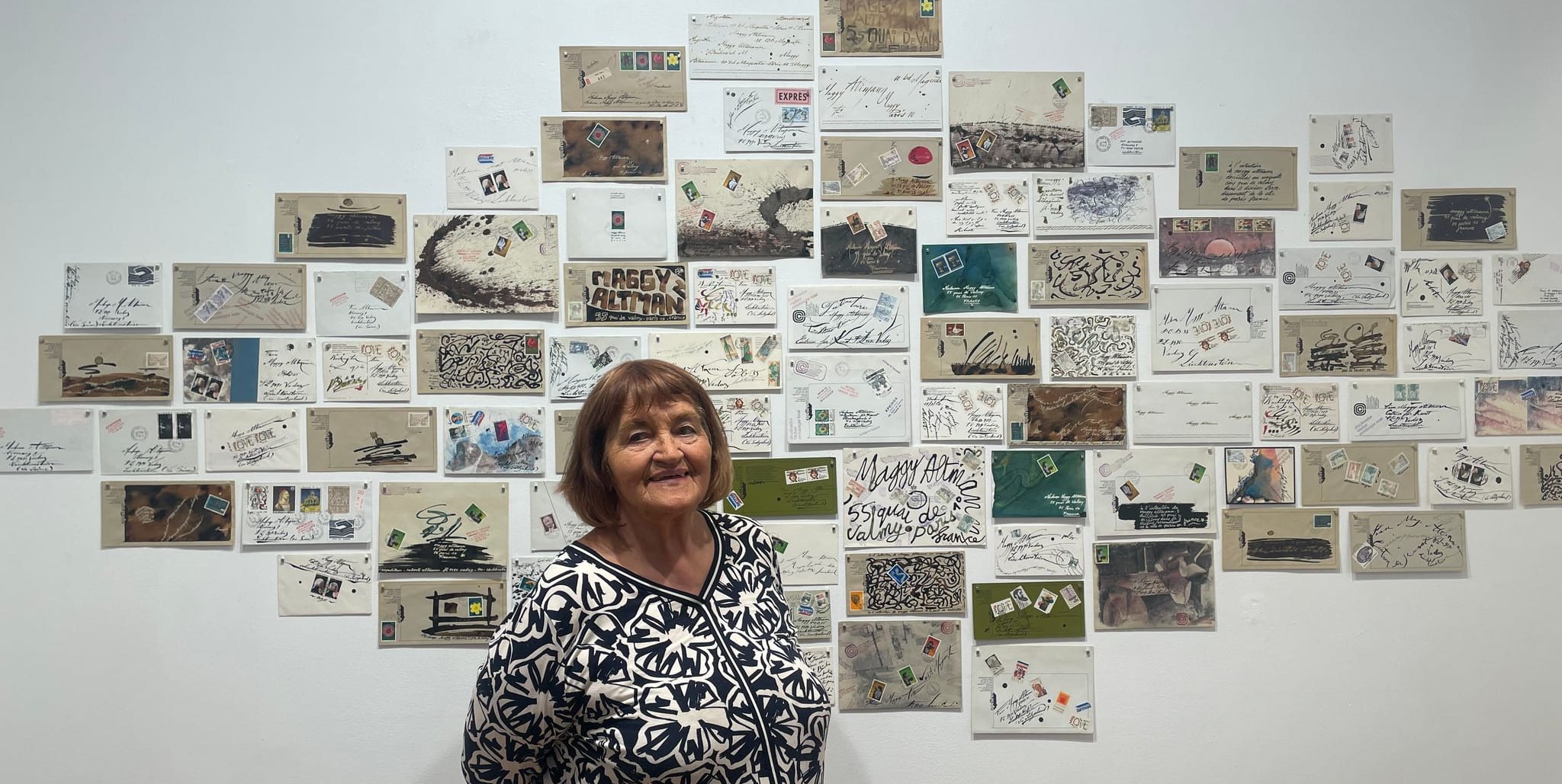 Maggy Mauritz vor der Wand mit den künstlerisch gestalteten Briefen von Roberto Altmann in Paris. Bild: P. Bausch