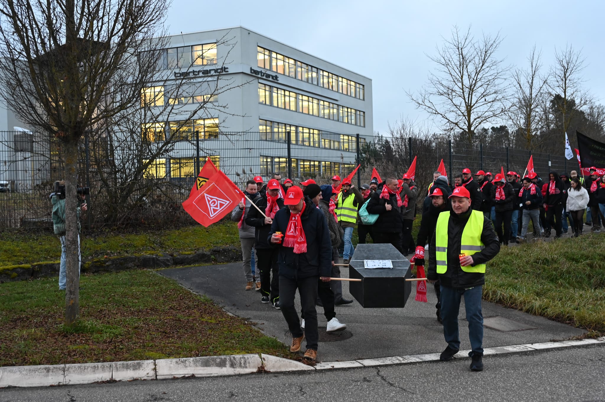 Der Demonstrationszug an der Ehninger Bertrandt-Zentrale.  Vorne rechts am symbolischen Sarg der Fahrerprobung Süd deren Betriebsratsvorsitzender Holger Lung.