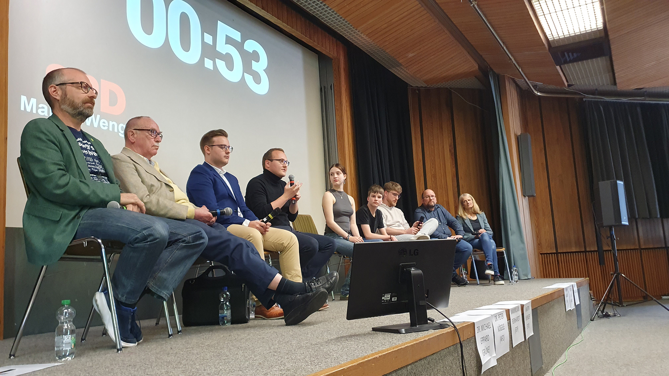 Auf dem Podium im VHS-Saal des Stiftsgymnasiums: Dr. Michael Eppard (Grüne), Dr. Peter Vögele (AfD), Maximilian Reinhardt (FDP), Martin Wenger (SPD), die Moderatoren Annika Baur und Marvin Diegruber, Robin Müller (Freie Wähler). Carsten Lau (Die Linke) und Maike Stahl (CDU, von links).