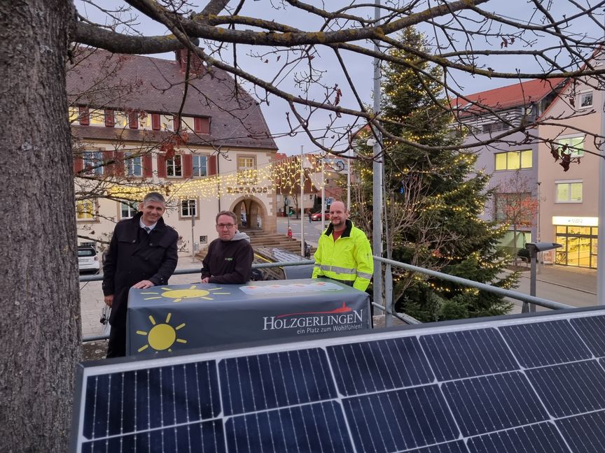 Holzgerlingens Bürgermeister Ioannis Delakos (von links), Seeeye-Geschäftsführer Rüdiger Schmidt und Stadt-Elektriker Volker Krauß vor dem leuchteten Weihnachtsbaum auf Rathausplatz. Eine auf dem Kirchplatz installierte PV-Anlage liefert in den kommenden Wochen den Strom für den Lichterglanz. Bild: Hamann