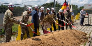 Lassen beim symbolischen Spatenstich schaufelweise Erde fliegen: Standortkommandant Kirk Alexander, Judd Sanford, der am 26. Juni dessen Nachfolge antritt, Dirk Frey (Bundesbau Baden-Württemberg), Günther Seher (technischer Bereichsleiter Ed. Züblin AG), Gisa Gaietto Ordnungsamts-Leiterin Böblingen), Justin Wetherwax (USACE), Tracie Russ (DeCA) und Anthony Polk (Militärkaplan, von links). Am Mikrofon: Michael Russ (DeCA).