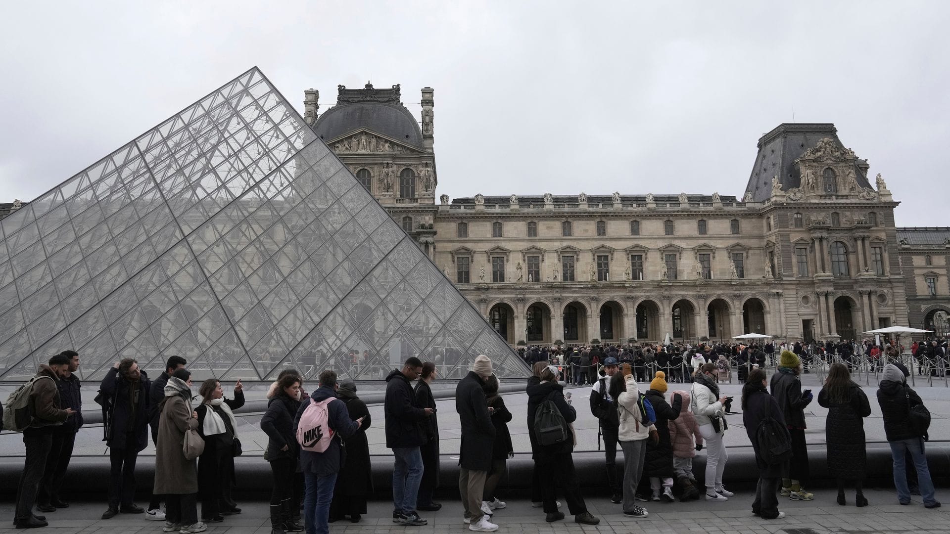 Menschen stehen vor den Louvre Schlange.
