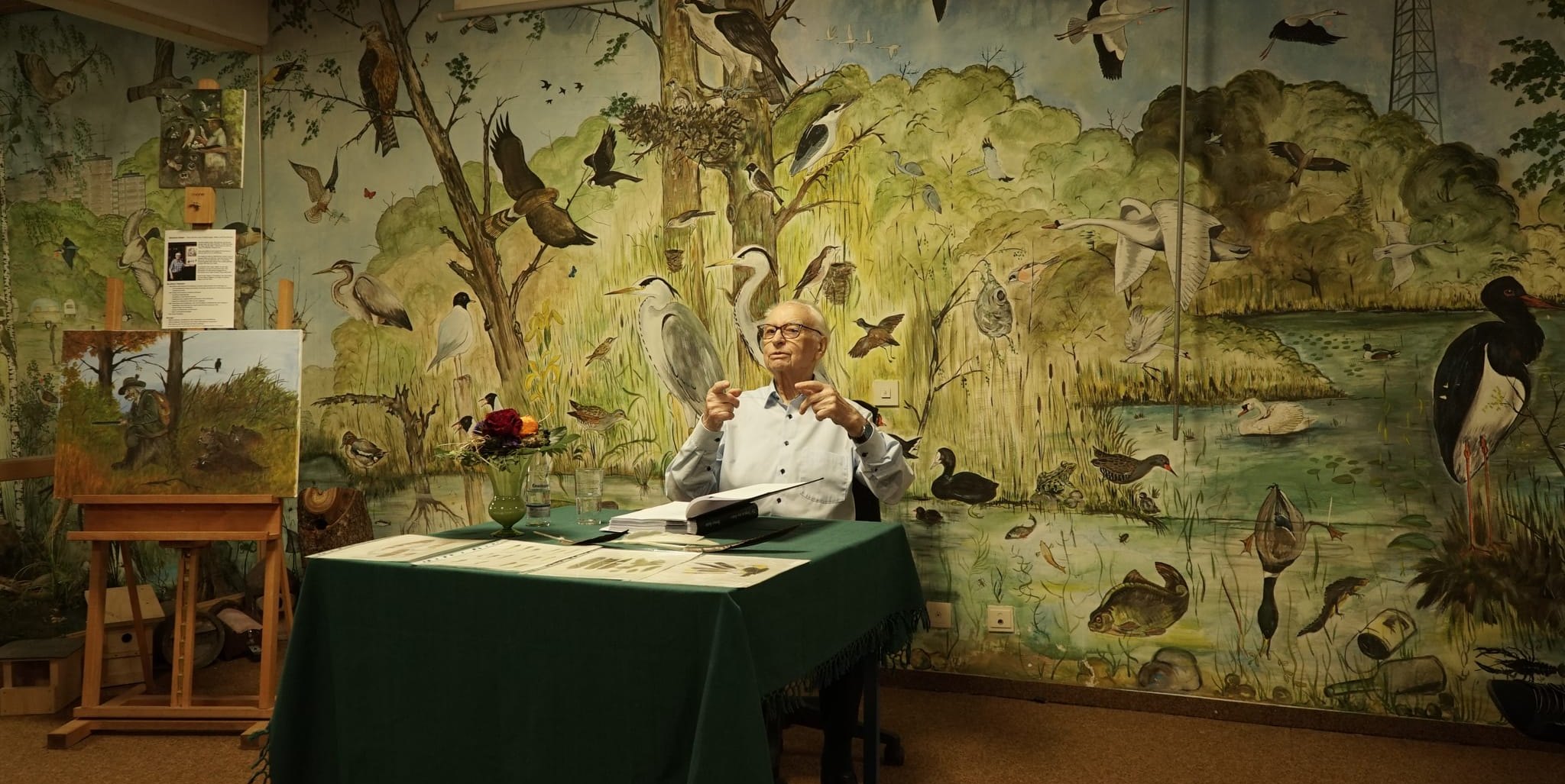 Eberhard Gabler bei seiner Lesung im Vogelzentrum vor der Wand, die er Anfang der 1980er Jahre selbst bemalt hat.