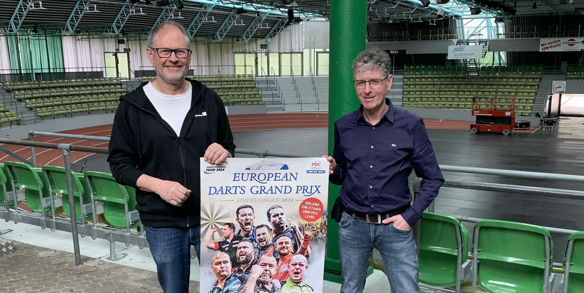 Uwe Dieterich (links) und Claus Regelmann präsentieren das Plakat des European Darts Grand Prix. Am Wochenende platzt der Glaspalast aus allen Nähten. Bild: Holzapfel