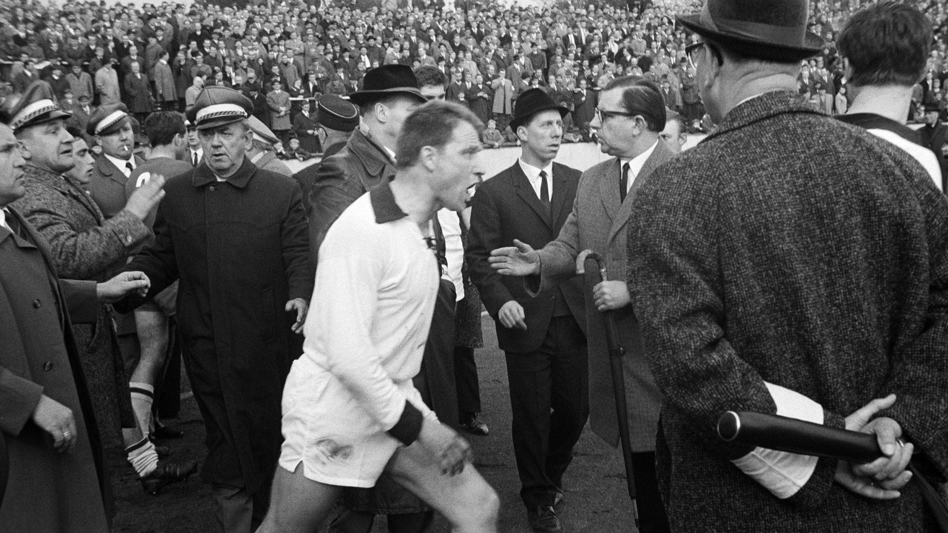 Man hört das Fluchen förmlich aus dem Bild  heraus: Karlheinz Mozin (SW Essen, Mi.)) wütend zwischen den Ordnern in den 1960ern bei einem Spiel der Regionalliga West.