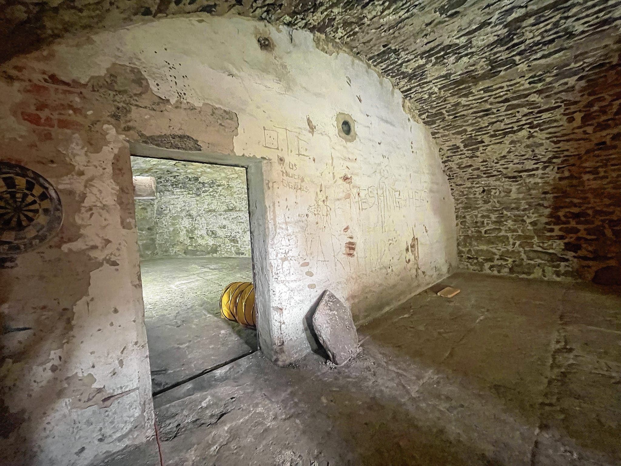 Der erste Keller: Die Mauer mit der Tür stammt aus den 30er Jahren. Die Dartscheibe und die Kritzeleien an der Wand sind allerdings nicht so alt: Wahrscheinlich stammen sie von Jugendlichen aus den 80er oder 90er Jahren, sagt Thomas Banholzer. Sie haben hier wohl gut gefeiert, wie auch unzählige Bierflaschen belegen.